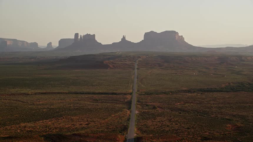Drone view of a road going through a valley in the desert toward mountains on the horizon