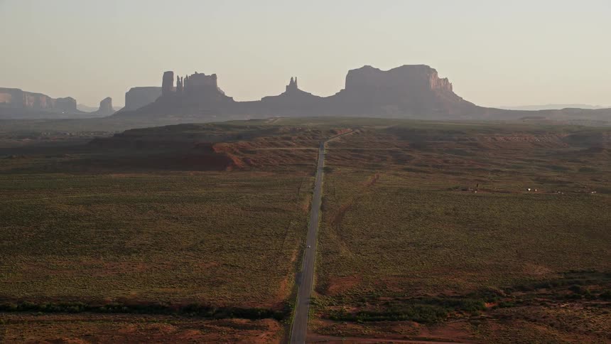 Aerial view of a road leading to mesas and buttes in the horizon