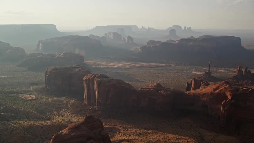 Drone view of mountain rock formations in the desert as the sun shines down casting a haze
