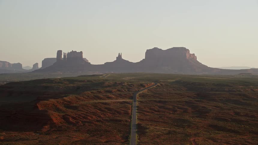 Aerial view of a road in a natural environment with canyons in the background during the late afternoon sun