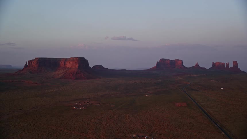 Aerial of a plain in the desert with mesa formations on the horizon