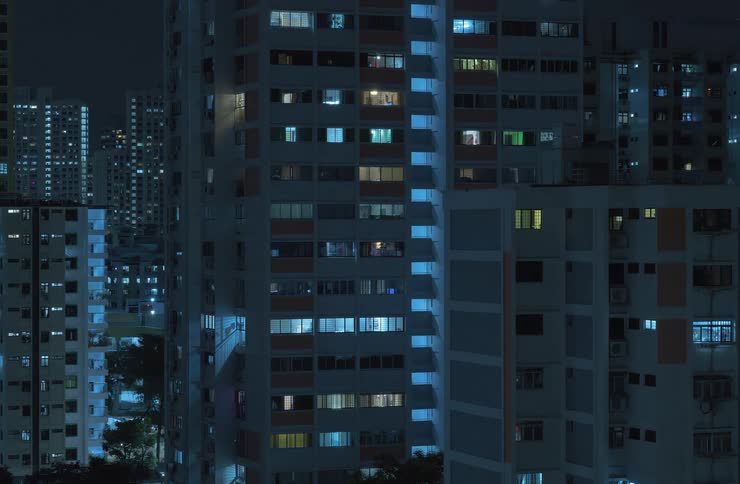 Exterior view of tall apartment buildings turning off lights at night