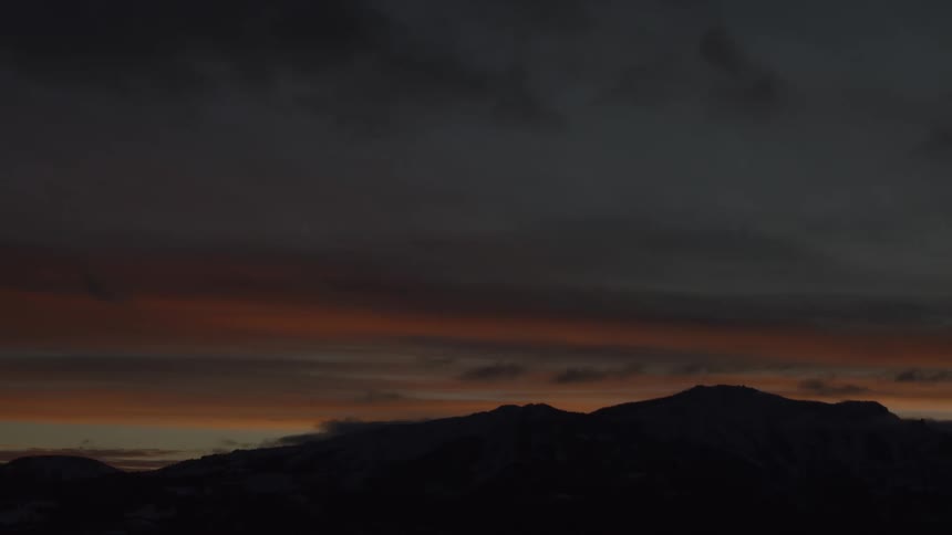 A silhouette of a mountain and a sky lit up with a morning sunrise