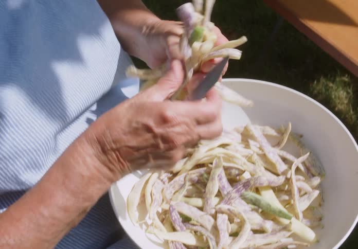 A person chopping vegetables with a small knife in a bowl
