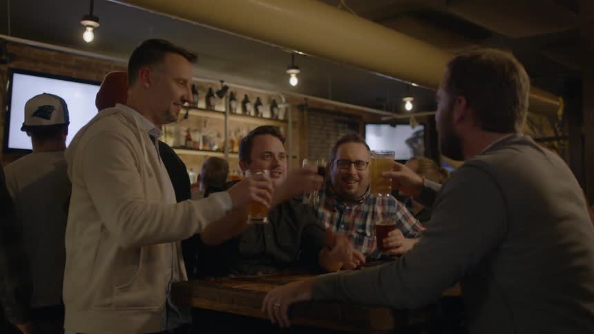 Group of men being served their beers and then cheering to each other