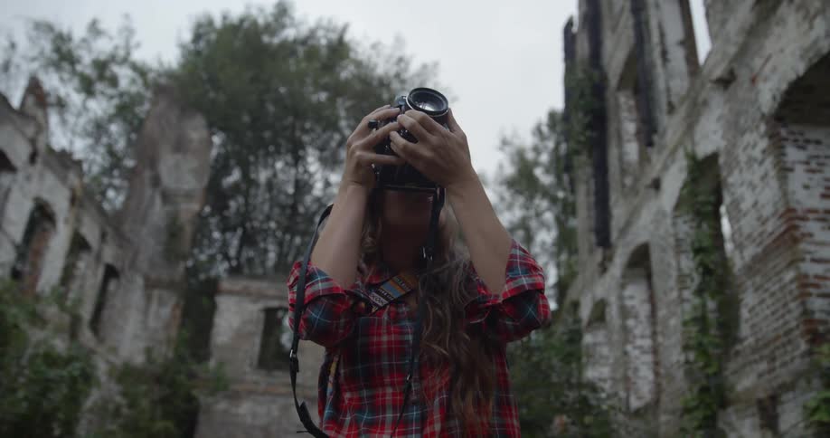A woman pushes the hair out of her face and focuses her camera