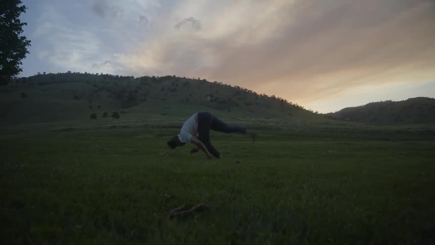 A man performs a series of acrobatic flips in a grassy field