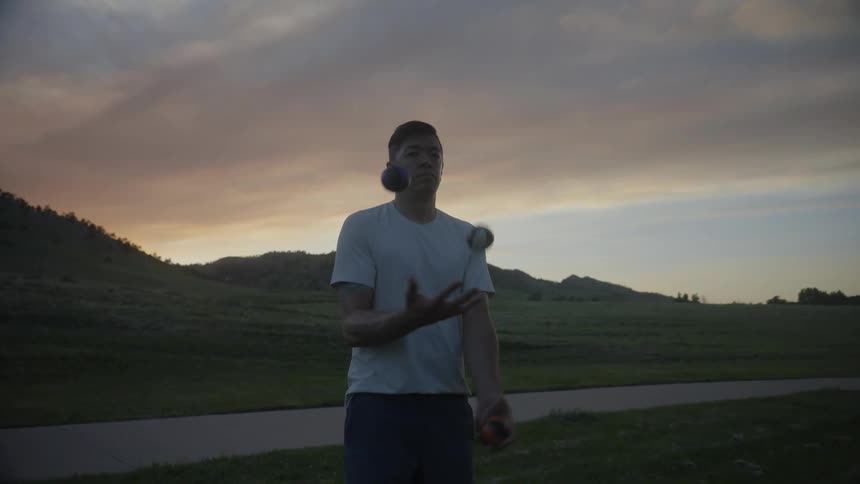 A man juggling balls in nature at sunset