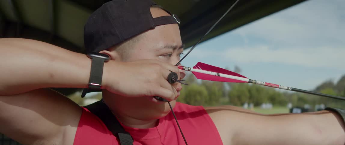 A man practices archery in a field during the day