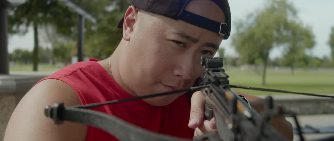 A concentrated man aiming with a crossbow in his hands