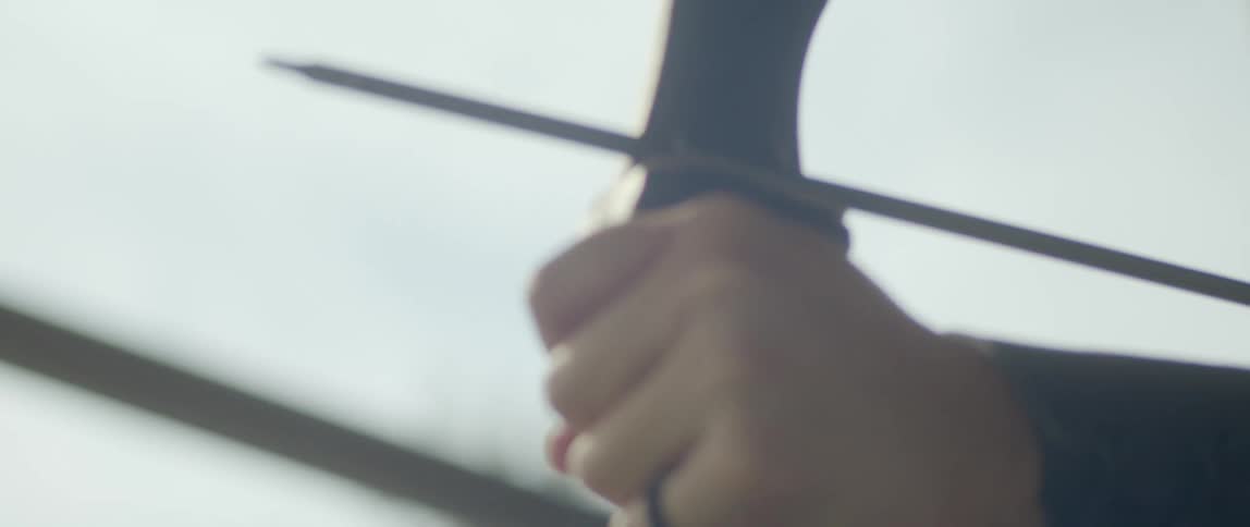 Archer takes aim to take a shot with bow and arrow