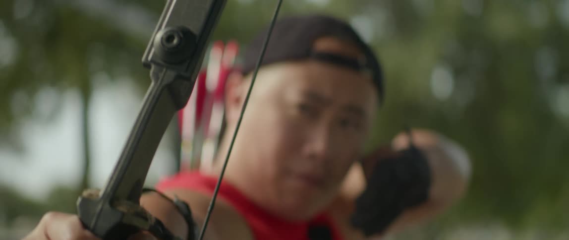 Archer aims and fires arrow while standing outdoors