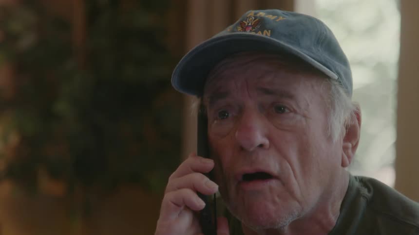 A man wearing a face cap talking aggressively on phone at midday