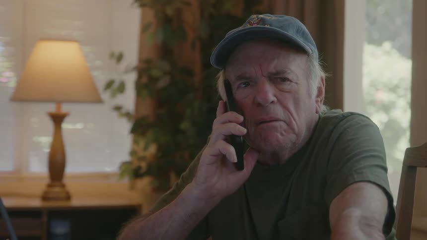 An elderly person talking on their cellphone with a facial expression of irritation