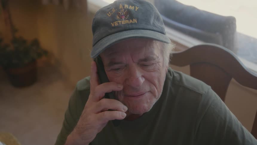 A gentleman is talking on the phone while sitting in a chair
