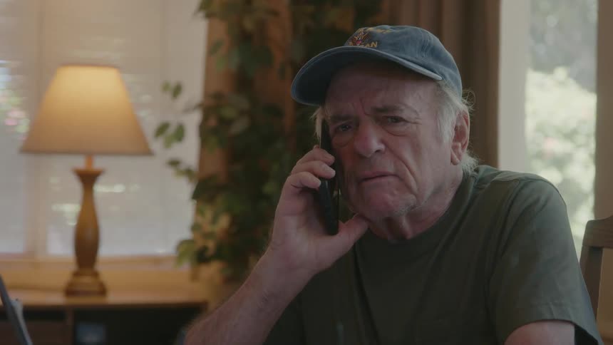 An elderly man talking on phone indoor at midday
