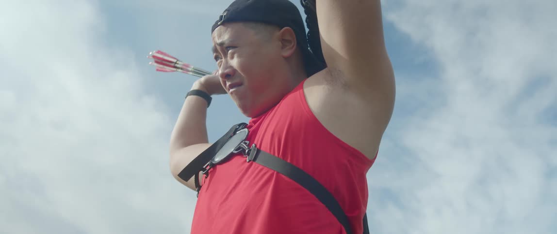 A man picking up arrows and placing them in a bag on his back