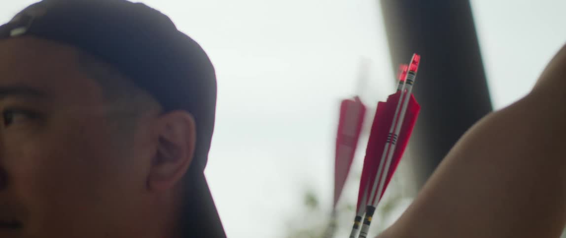 A man draws an arrow from a quiver at midday
