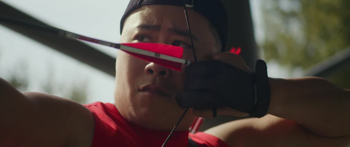 A man aiming at the target with a bow in his hands