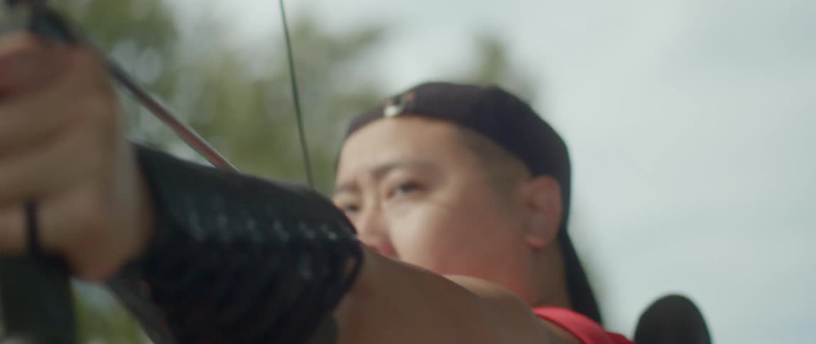 An asian person preparing and releasing an arrow with their bow