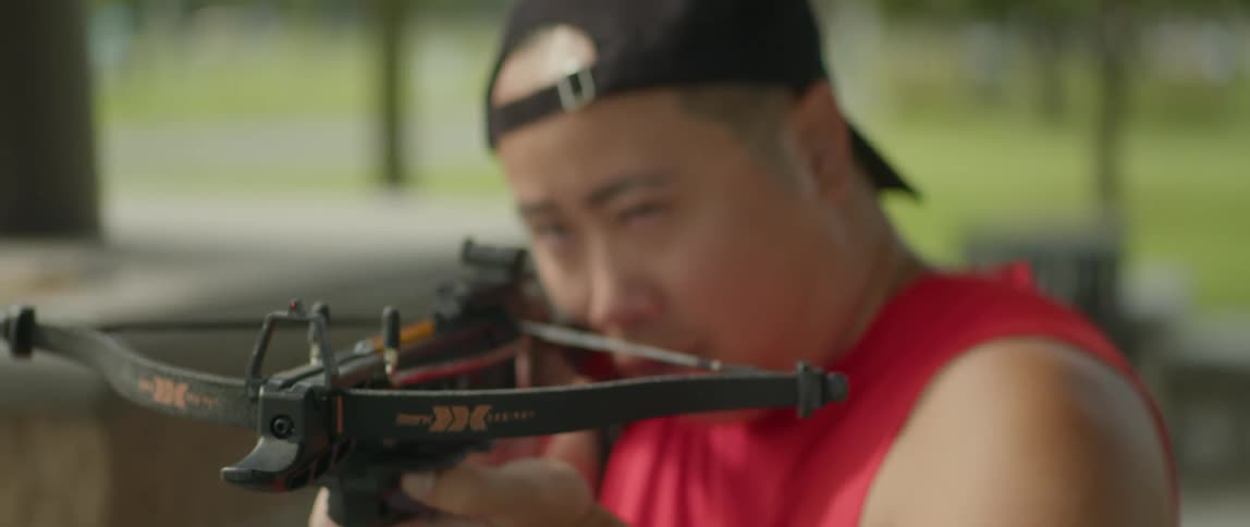 A man is aiming at the target with a crossbow