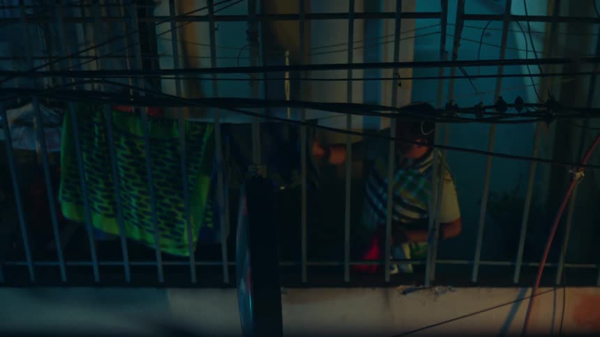 An elderly person collecting clothes from the clothesline hanging outside the window of the house