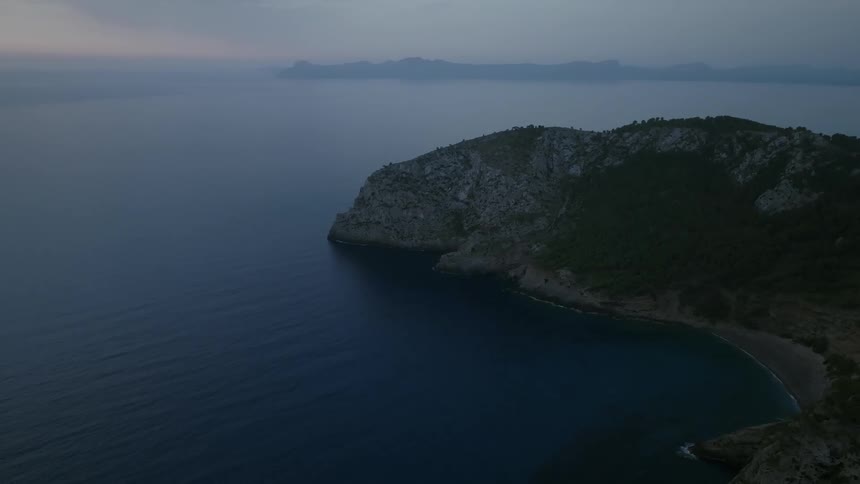 Aerial of a coastal beach with a mountain at dusk