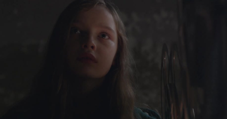 Young girl looking forward as a projector spins beside her