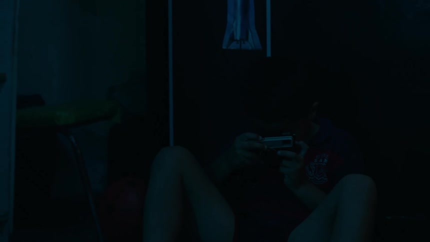 A young boy playing with an electronic device in a dark room
