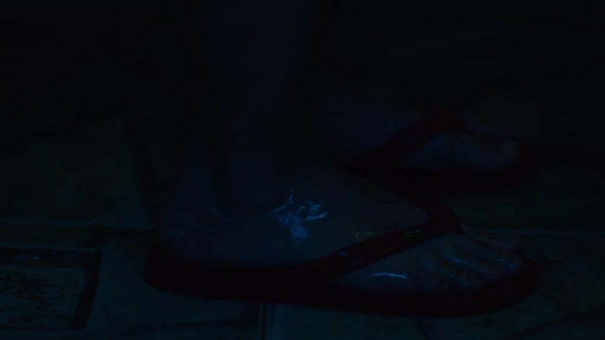 Closeup of a persons feet in wet slippers during the night