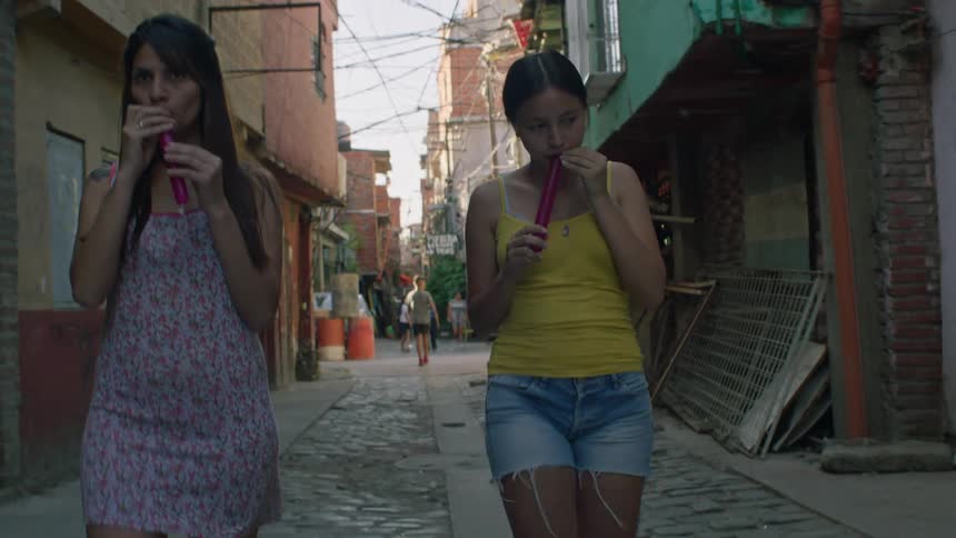Two friends walking on the neighborhood street in the outskirts while enjoying ice cream
