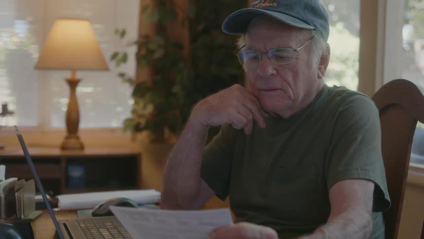 Elderly person picking up a document reading it and making a facial expression of indignation