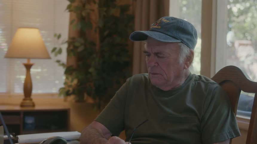 An elderly man looks at a paper and has facial expressions of nervousness and concern