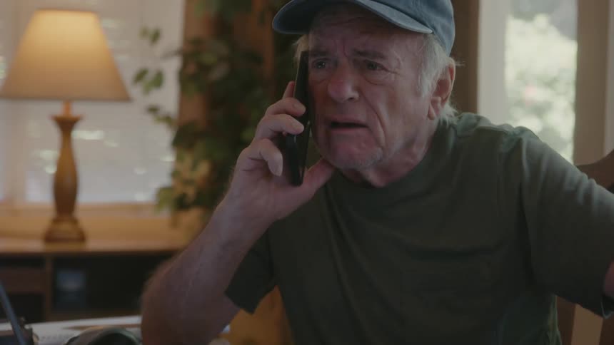 Elderly person talking on the phone with a facial expression of indignation