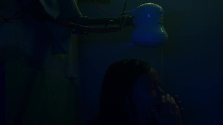A woman is turning on the shower and taking a bath in a dark room