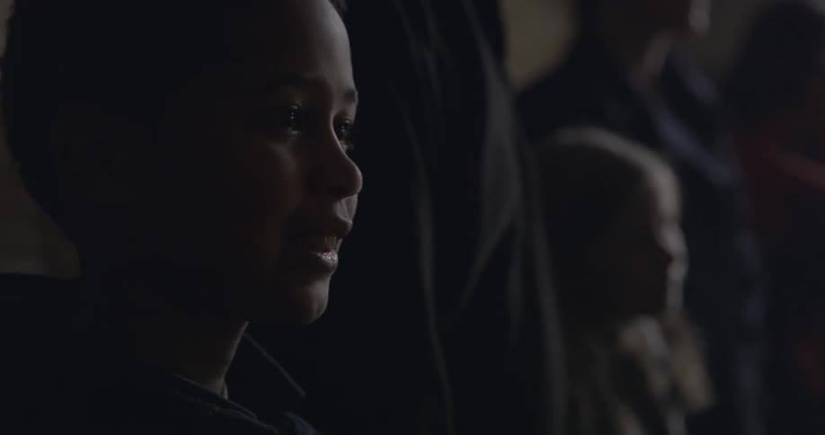 A child is smiling standing in line with other people