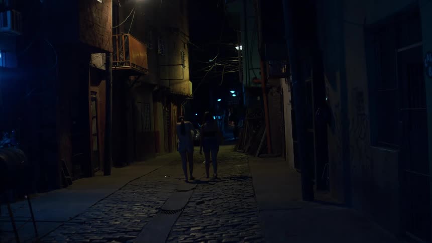 Two women walking away in a residential neighborhood at night