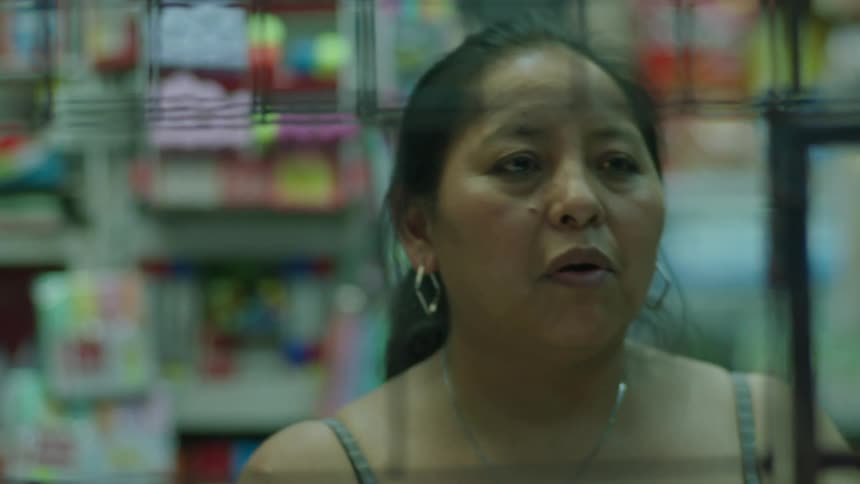 A woman selling a soft drink from her small market and then jotting down something with a pen
