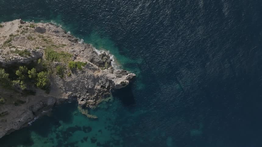 Aerial view of a rocky peninsula with turquoise blue sea