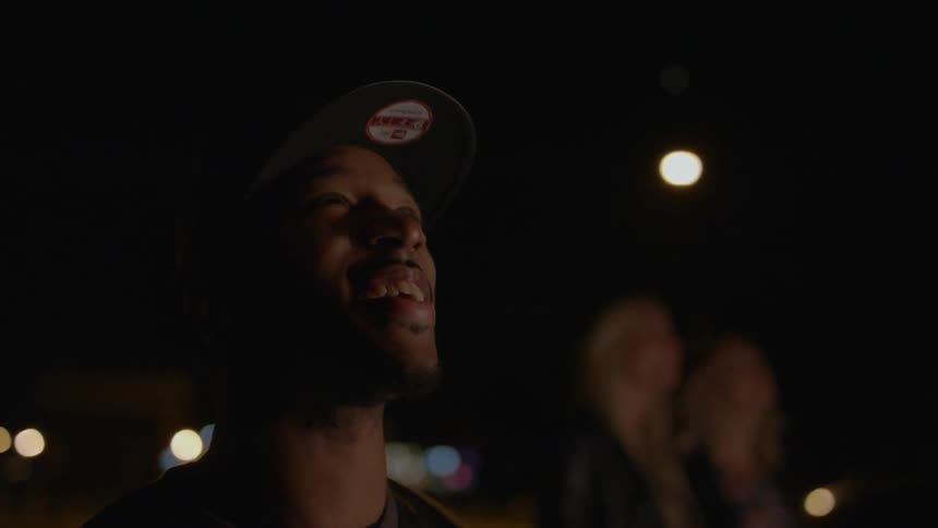 People standing outside at night looking happily into the sky at something