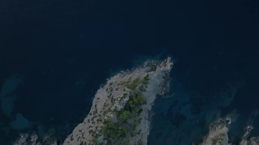 Aerial view of a rocky island in the middle of a sea with crystalclear waters