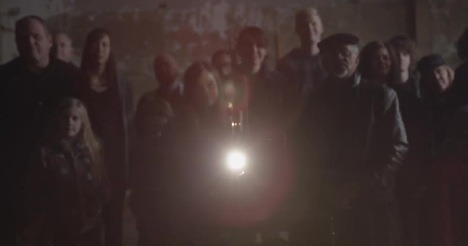 A group of people stand behind a working projector