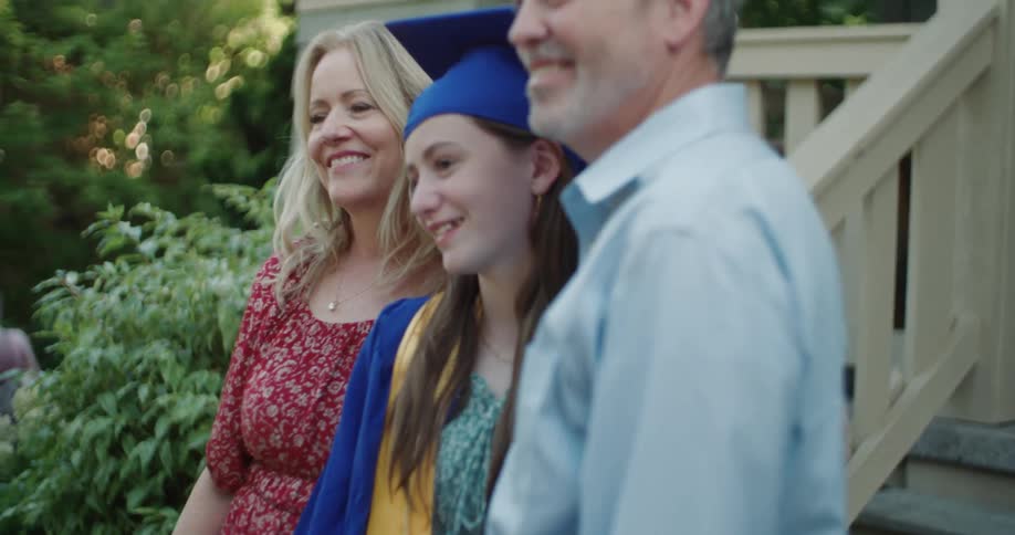 A girl is posing with her parents for graduation