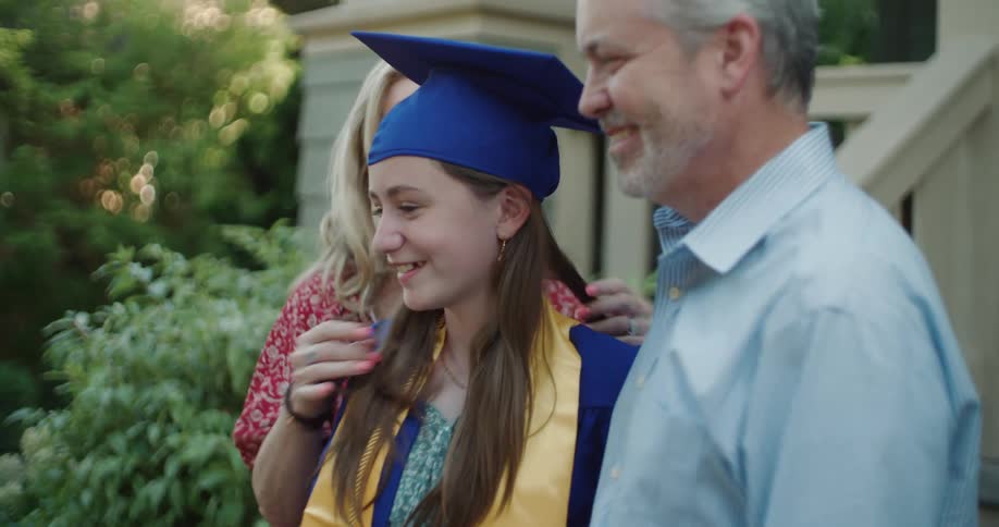 A teenage girl in graduation uniform is posing with her parents
