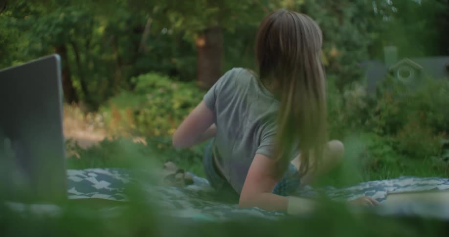 A teenage girl is lying down typing on a cell phone and then puts it down and turns over