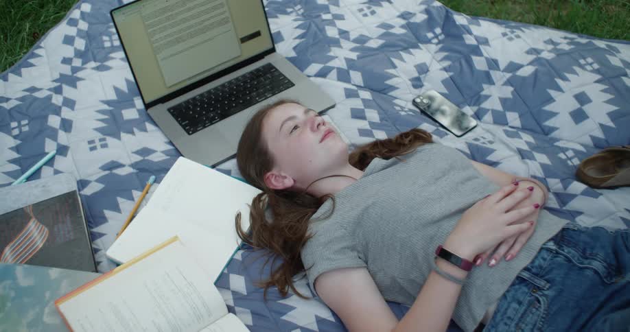 A girl lying on the grass using her cell phone
