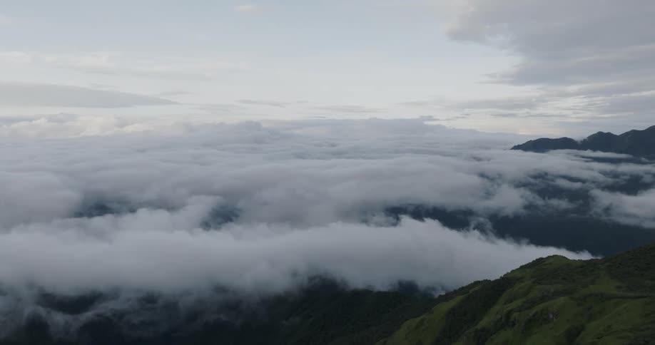 Aerial of clouds hovering over a wide mountain scape