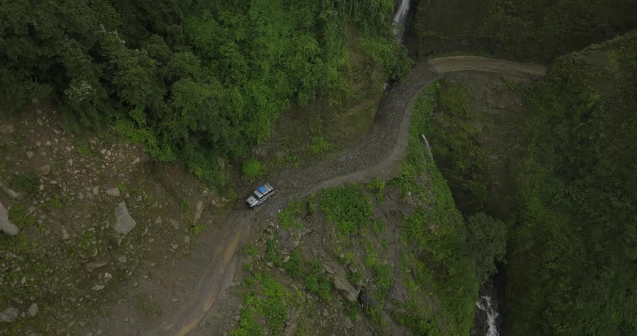 A car moving on a narrow road over a waterfall at midday
