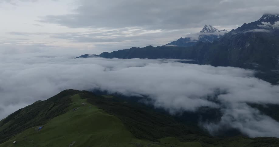 Aerial view of hills under the clouds next to a mountain range