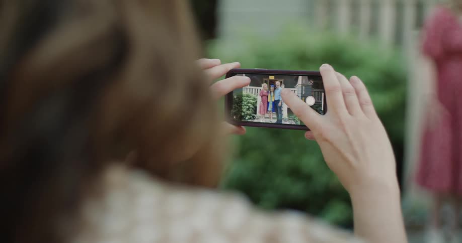 Close up of a woman taking a picture with her cellphone of a small group of people